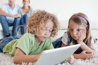 Serious children using a tablet computer while their happy paren