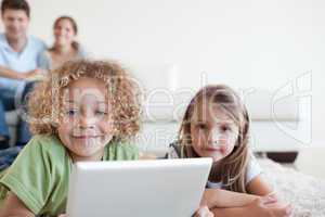 Smiling children using a tablet computer while their happy paren
