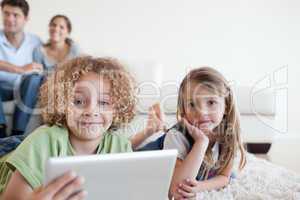 Happy children using a tablet computer while their happy parents