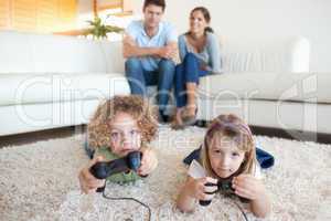 Cute children playing video games while their parents are watchi