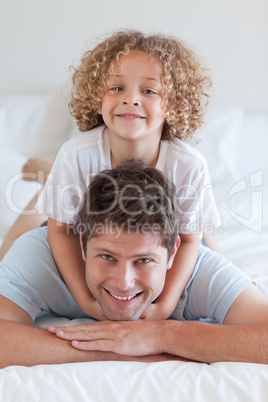 Smiling father and child lying on bed