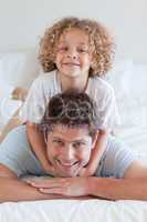 Smiling father and child lying on bed