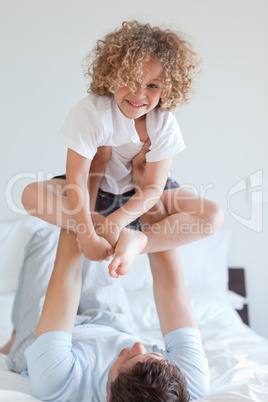 Father lifting child on bed