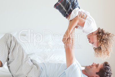 Side view of father lifting child on bed