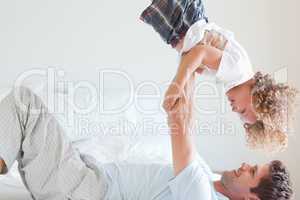 Side view of father lifting child on bed