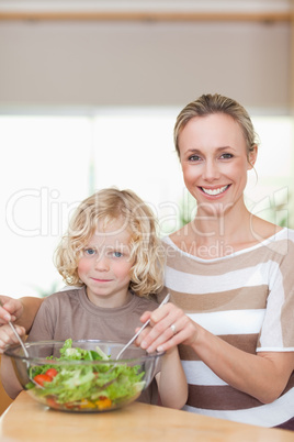 Smiling mother and son stirring salad
