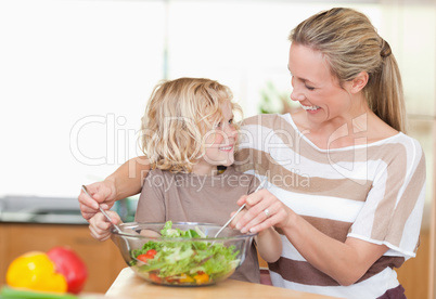 Happy mother and son preparing salad