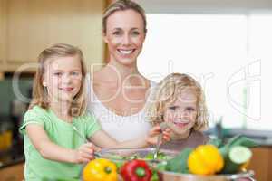 Smiling woman with her children preparing salad