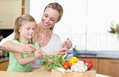 Mother and daughter stirring salad