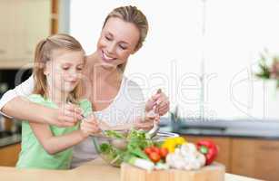 Mother and daughter stirring salad