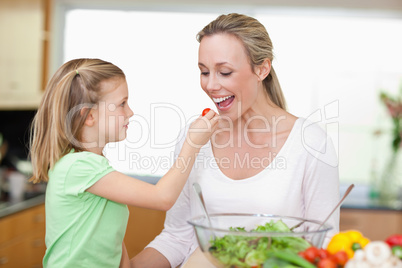 Girl feeding her mother with tomato