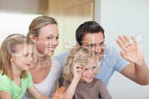Family waving their hands in the kitchen