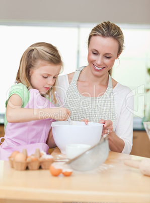 Smiling mother and daughter preparing dough for cookies