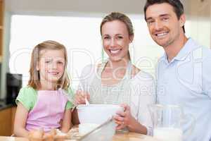 Girl preparing dough with her parents