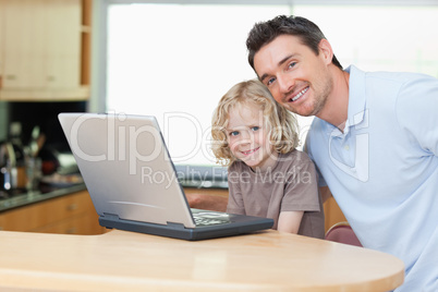 Father and son with notebook in the kitchen