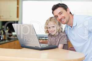 Father and son with notebook in the kitchen