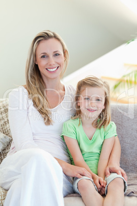 Mother and daughter sitting on sofa together
