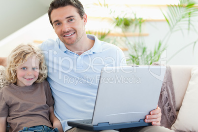 Father and son on couch with laptop