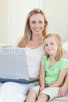 Mother and daughter with laptop on sofa