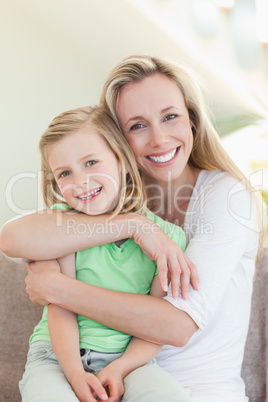 Mother hugging her daughter on couch