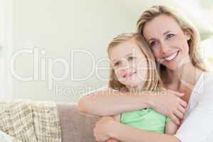 Mother embracing daughter on couch