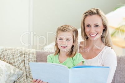 Mother and daughter reading a magazine on the sofa