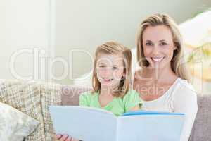 Mother and daughter reading a magazine on the sofa