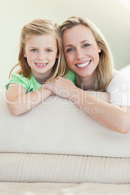 Happy smiling mother and daughter on the sofa