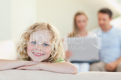 Smiling boy with parents in the background