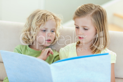 Siblings reading magazine on the couch