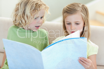 Siblings on the sofa reading magazine
