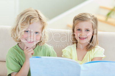 Siblings on the couch reading magazine