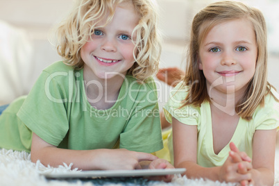 Siblings using tablet on the floor