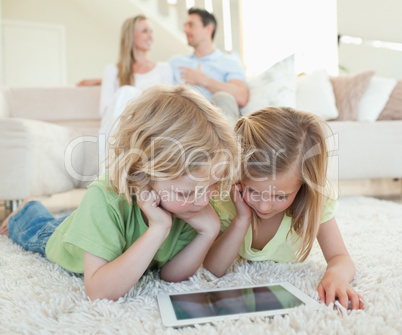 Children on the floor with tablet and parents behind them