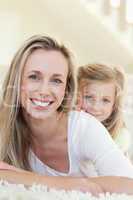 Smiling mother and daughter on the carpet