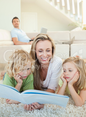 Mother reading magazine with her children on the floor