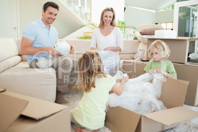 Family unpacking cardboard box in the living room