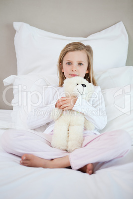 Girl hugging her teddy on the bed