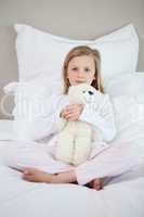 Girl hugging her teddy on the bed