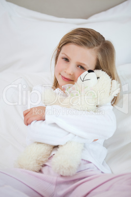 Girl embracing her teddy on the bed