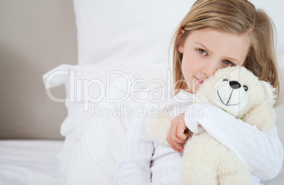 Girl with her teddy sitting on the bed