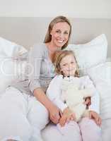 Mother and daughter sitting on bed