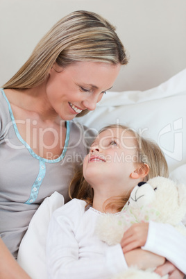 Mother hugging her daughter on the bed