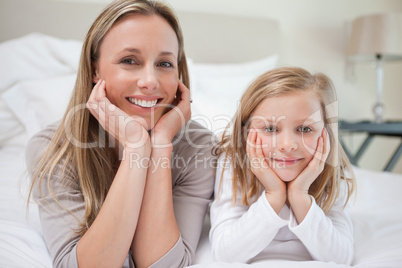 Smiling mother and daughter lying on the bed