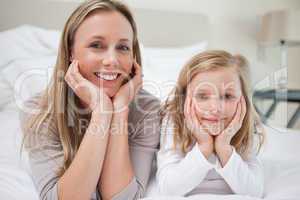 Smiling mother and daughter lying on the bed