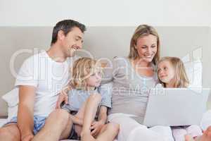 Family using laptop on the bed