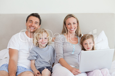 Family sitting on the bed with laptop