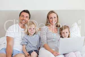 Family sitting on the bed with laptop