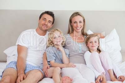 Smiling family sitting on the bed