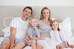 Smiling family sitting on the bed